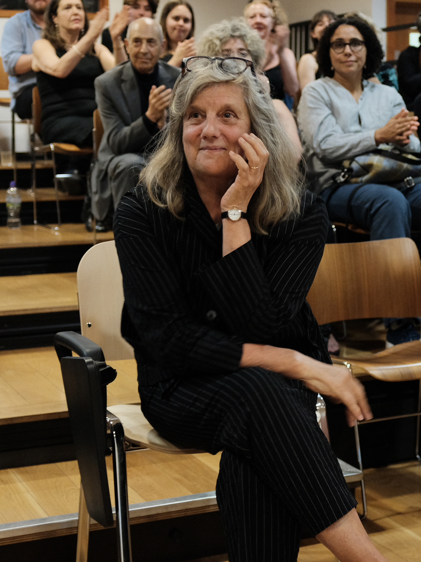 A photo of Fiona Macintosh at her retirement celebration. She is sitting in the audience listening to tributes in her honour. 